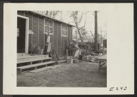 [recto] Mrs. T. Arima busily prepares her doorstep garden in Block 7. Besides odd plants and stump arrangements, there will be a pool with goldfish. ;  Photographer: Parker, Tom ;  Denson, Arkansas.