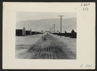 [recto] Manzanar, Calif.--Street scene looking east toward the Inyo Mountains at this War Relocation Authority center. The children are coming to ...