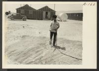 [recto] (Site No. 1) --Jim Morikawa sprinkling in an attempt to settle the dust at this War Relocation Authority center for evacuees of Japanese ancestry. ;  Photographer: Clark, Fred ;  Poston, Arizona.