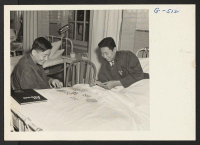 [recto] Pvts. Kazuto Yoshioka and Wallace Hisamoto have a game of cards in the ward at Walter Reed Hospital. Yoshioka lost his right arm below the elbow and Hisamoto his left leg, both in action with the 100th Battalion in Italy. ;  Photographer: Van Tassel, Gr