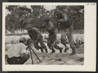 [recto] Tom Parker, WRA Photographer, makes a close-up movie of Japanese-American soldiers at Camp Shelby running the obstacle course. The 442nd ...