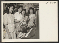 [recto] Gathered around the piano for some singing are several members of the Yamasaki family with a couple of their friends. ...