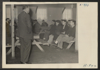 [recto] Robert Cozzens, WRA Ass't Field Director, is here explaining to a group of evacuees of Japanese descent the purpose of registration. All centerites between the ages of 18 and 38 registered at this time. ;  Photographer: Stewart, Francis ;  Manzanar, C