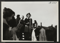 [recto] Yo Ikeda raises her beautiful voice during ceremonies which open the football game between Topaz and Fillmore high schools at Topaz Relocation Center, November 11, 1943. ;  Topaz, Utah.