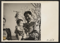 [recto] Henry Mitarai, 36-year-old successful large-scale farm operator, holding the youngest of his four daughters prior to evacuation. These residents of Japanese ancestry will spend the duration at War Relocation Authority Centers. ;  Photographer: Lange, Do