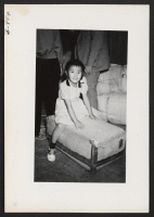 [recto] Etsu Nakamura, 30-11-D, one of the young arrivals on the first train from Tule Lake, waited while her father claimed his checkable baggages after inspection in one of the Recreation Halls. ;  Photographer: Lynn, Charles R. ;  Denson, Arkansas.