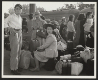 [recto] Families of Japanese ancestry with their baggage at railroad station awaiting the arrival of special train which will take them to the Merced Assembly Center about 125 miles away. ;  Woodland, California.