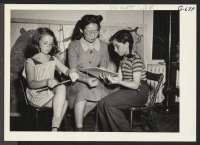 [recto] Two little girls at Philadelphia's Hope Day Nursery eagerly turn to their teacher, Chico Sakaguchi, formerly of Manzanar, for assistance. ...