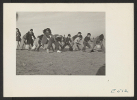 [recto] Over and under with a volley ball is an exciting game of these grade school children during the morning recess. ;  Photographer: Parker, Tom ;  Amache, Colorado.