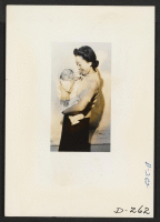 [recto] This picture of mother and child was taken for evacuee use. This picture is interesting from a documentary angle, however, for it shows the proud mother holding the doll-like featured child. ;  Photographer: Stewart, Francis ;  Newell, California.