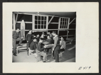 [recto] In a block laundry at the Amache Relocation Center, a group of 13 to 16 year old boys meet to organize a Hi Y club. The names are (extreme left), Tad Mukaihata, advisor, (standing right) Masao Yusaki, newly elected president. ;  Photographer: Parker, To