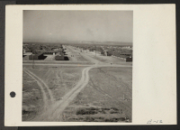 [recto] Looking down a main thoroughfare at the Topaz Relocation Center. ;  Photographer: Parker, Tom ;  Topaz, Utah.