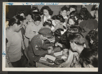 [recto] Sgt. Kuroki swamped by autograph seekers in high school class rooms, immediately following his talk to the student body in the auditorium. ;  Photographer: Aoyama, Bud ;  Heart Mountain, Wyoming.