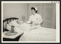 [recto] Miss Chiyiko Yamamoto, a cadet nurse enrolled in the Seton School of Nursing, takes a patient's temperature and pulse as ...