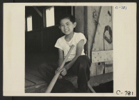 [recto] Manzanar, Calif.--Evacuee boy waiting at the entrance of the Recreational Hall at this War Relocation Authority center. He is anxious for the baseball team to assemble. ;  Photographer: Lange, Dorothea ;  Manzanar, California.