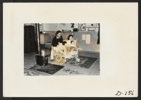 [recto] An evacuee family spends a quiet evening in their barracks. The decoration of this apartment is quite typical and shows the home made furniture, shelves, bookcases and other furniture. ;  Photographer: Stewart, Francis ;  Newell, California.