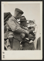 [recto] San Pedro, Calif.--Father and son evacuees of Japanese ancestry talk things over with military policeman prior to leaving for assembly center at Arcadia, California. ;  Photographer: Albers, Clem ;  San Pedro, California.