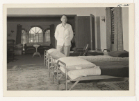 [recto] The Sturge Hostel at 26 South Humboldt, San Mateo, California. Mr. Frank Murai, a recent arrival from Heart Mountain, is selecting a bed in the men's dormitory. ;  Photographer: Iwasaki, Hikaru ;  San Mateo, California.