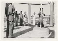 [recto] As one scout sounds the bugle call, others stand at attention while the flag is lowered at the Servicemen's Monument atop a hill which overlooks the camp. ;  Rivers, Arizona.