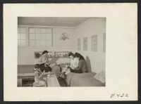 [recto] Sunday afternoon and the three girls who occupy this barracks room relax. The furniture, the book niches, flower pot and print mats are all made by the girls from scrap lumber and scrap pieces of wall board. ;  Photographer: Parker, Tom ;  Amache, Col