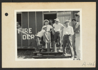 [recto] Poston, Ariz.--Evacuee firechief, Tom Nishimura, discusses Army type fire extinguisher with his staff at this War Relocation Authority center. ;  Photographer: Clark, Fred ;  Poston, Arizona.
