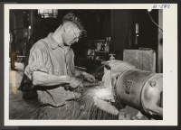 [recto] George Dotimoto, Japanese-American evacuee from the Gila River Relocation Center working at a power grinder in the G. & N. ...