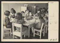 [recto] Children are taught democratic games in the nursery school at the Relocation Center. All desks, chairs, and other furnishings are made in the furniture factory, by evacuee workers. ;  Photographer: Stewart, Francis ;  Manzanar, California.