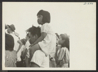 [recto] A little evacuee of Japanese descent gets a ride on her father's shoulders. ;  Photographer: Stewart, Francis ;  Poston, Arizona.