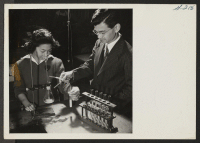 [recto] Scene in the Chemistry class at the Heart Mountain High School, as Kaoru Inouye, instructor, is showing student Sumi Tam[...] a step in one of the Chemistry experiments. ;  Photographer: Iwasaki, Hikaru ;  Heart Mountain, Wyoming.