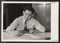 [recto] Eugene Y. Komo at work at a drafting table in the design room of the Superior Type Company, War Contract ...