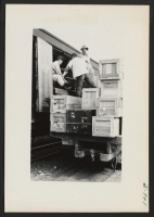 [recto] Evacuee loading crews are seen filling a segregation baggage car with checkable baggages bound for Tule Lake. ;  Photographer: Lynn, Charles R. ;  Dermott, Arkansas.