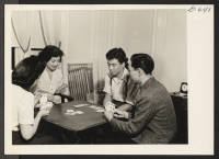 [recto] Mr. and Mrs. Ray Komai, formerly of Los Angeles (center), spend an evening in their New York apartment playing bridge ...