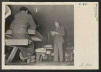 [recto] Sergeant Victor Tierman explains the purpose of registration to a group of Japanese and Japanese-Americans, who were evacuated from west coast areas and are now residing at the Manzanar Center. ;  Photographer: Stewart, Francis ;  Manzanar, California