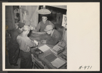 [recto] Mechanics check parts and tools from the tool room, in the garage, at this relocation center. All repair work on cars, trucks, and other motor vehicles is done by evacuee labor. ;  Photographer: Stewart, Francis ;  Newell, California.