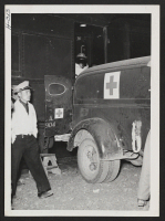 [recto] A bed ridden transferee, on trip 15 from Topaz to Tule Lake, is moved directly from the pullman car to an awaiting ambulance. He will be moved directly to the Tule Lake Hospital. ;  Photographer: Mace, Charles E. ; , .