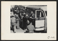 [recto] Byron, Calif.--Farm families of Japanese ancestry boarding buses for Turlock Assembly Center 65 miles away. An official of the WCCA is checking the families into the bus by number. ;  Photographer: Lange, Dorothea ;  Byron, California.