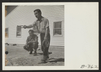 [recto] Henry Yamashiro watches Tad Horita pitch a game of horse shoes. Members of the fire department, like members of all fire departments, are experts at this American game. ;  Photographer: Stewart, Francis ;  Topaz, Utah.