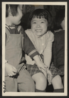 [recto] A bashful little girl, whose parents are American born citizens of Japanese ancestry, is tickled at posing for her picture in a nursery school at the Heart Mountain Relocation Center. ;  Photographer: Parker, Tom ;  Heart Mountain, Wyoming.