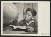 [recto] A globe is used by this pupil in the high first grade to assist in his geography lesson. ;  Photographer: Stewart, Francis ;  Topaz, Utah.