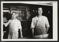 [recto] Norima Kitaoka and Yoshito Sera pose for the photographer beside one of the giant ranges in the kitchen at the ...