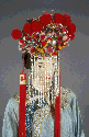 Headress, wedding, stiffened red silk, very ornate with sequins, fringe, fur pom poms and beads. Frontal area has fringe made of 10" long strands of imitation pearls and a long thin beads.  Hanging from each side are long red tassels. Chinese, Circa 1900.