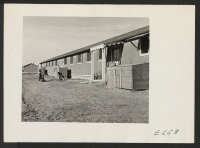 [recto] A typical barracks building resident of the first apartment has constructed from scrap lumber a storm porch and added a touch with mock shutters at the windows. ;  Photographer: Parker, Tom ;  Amache, Colorado.