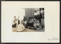 [recto] Poston, Ariz.-- Norris James, WRA representative, gives instructions and assignments to the newspaper staff of evacuees of Japanese ancestry at this War Relocation Authority center. ;  Photographer: Stewart, Francis ;  Poston, Arizona.