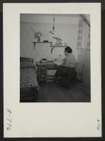 [recto] All the furniture in this evacuee apartment was constructed from scrap material. The wall paper, drapes and other furnishings were purchased from a mail order house. Mrs. Eizo Nishi, housewife. Former residence: Seattle, Washington. ;  Photographer: Ste