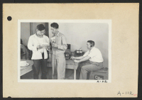 [recto] Poston, Ariz.--Geo. Kith [George Kita], evacuee at this War Relocation Authority center, and Norris James, WRA official, at the microphone. ;  Photographer: Clark, Fred ;  Poston, Arizona.