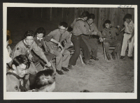 [recto] A farewell party of the Boy Scouts, Troop 97, held in honor of their Scout Master, Mr. and Mrs. Eddie Sakaniwa. The picture is where the group is playing Post Office. Mr. and Mrs. Sakaniwa are leaving the center for Tule Lake. ;  Photographer: Okano, To