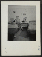 [recto] All the furniture in this evacuee apartment was constructed from scrap material. The wall paper, drapes and other furnishings were purchased from a mail order house. (L to R) Mrs. Eizo Nishi, housewife, and Eime, four, daughter. Former residence: Seattle,