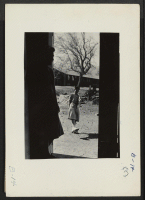 [recto] Manzanar, Calif.--Yaeko Yamashita (in doorway) watches Fugiko Koba trying a new pair of geta, which are stilt-like sandals specially useful in dust. They are evacuees of Japanese descent now living at this War Relocation Authority center. ;  Photographe