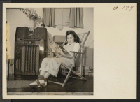 [recto] Lucy Yonemitshu, former student from Los Angeles, California, enjoys a few free moments from her household duties and listens to swing music from her familiar and favorite Los Angeles radio station. ;  Photographer: Stewart, Francis ;  Manzanar, Calif