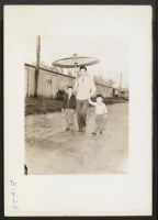 [recto] Arcadia, Calif.--Japanese parasol for spring showers at Santa Anita Park assembly center. Evacuees later are transferred to War Relocation Authority centers for the duration. ;  Photographer: Albers, Clem ;  Arcadia, California.